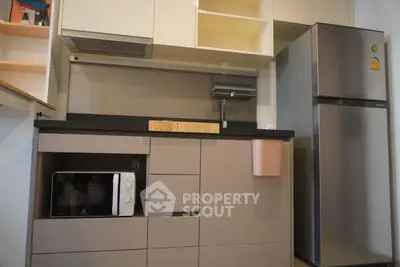 Modern kitchen with sleek cabinets, microwave, and stainless steel fridge