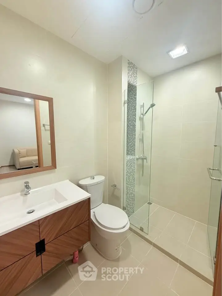 Modern bathroom with glass shower and wooden vanity in a contemporary apartment.