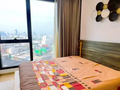 Modern bedroom with city view, featuring stylish decor and large window for natural light.