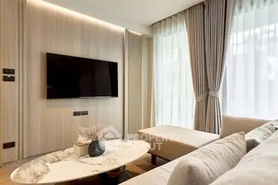 Modern living room with elegant decor and large TV, featuring a cozy sofa and stylish coffee table.