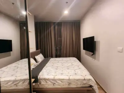 Modern bedroom with mirrored wardrobe and wall-mounted TV in a cozy apartment.