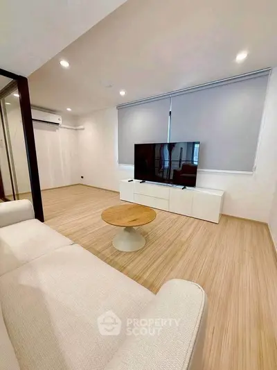 Modern living room with sleek design, featuring a large TV and stylish furniture.