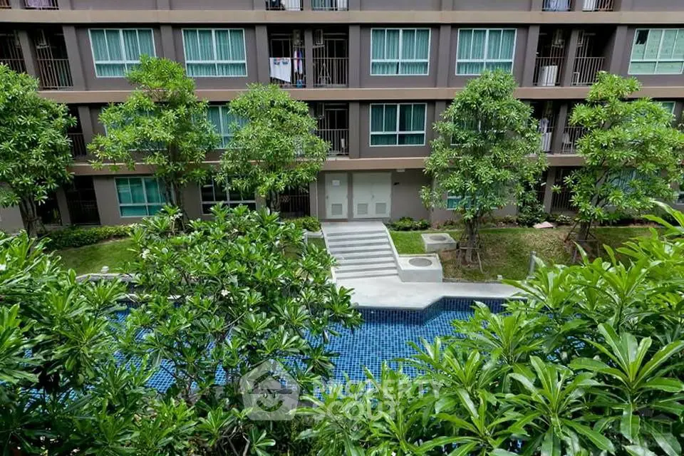 Modern apartment building with lush garden and inviting pool view.