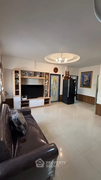 Spacious living room with modern decor and large TV unit, perfect for family gatherings.