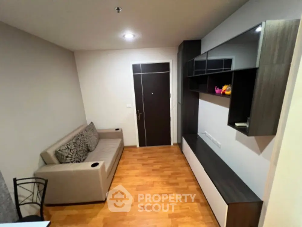 Cozy living room with modern furniture and wooden flooring in a compact apartment.