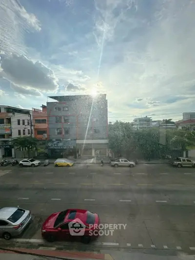 Urban street view with residential buildings and parked cars under a bright sky