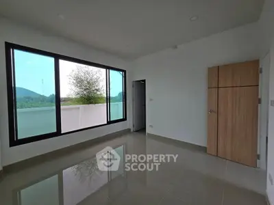 Spacious room with large window offering scenic views, perfect for natural light lovers.