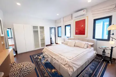 Spacious bedroom with elegant decor and natural light, featuring a large bed and stylish furnishings.