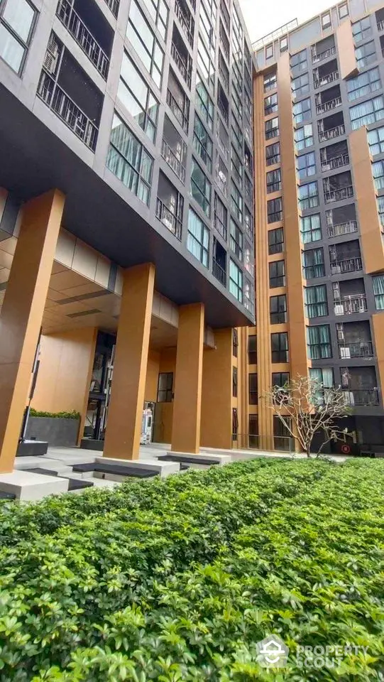 Modern high-rise apartment building with lush green landscaping