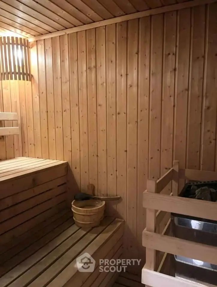 Luxurious wooden sauna interior with warm lighting and traditional sauna bucket.