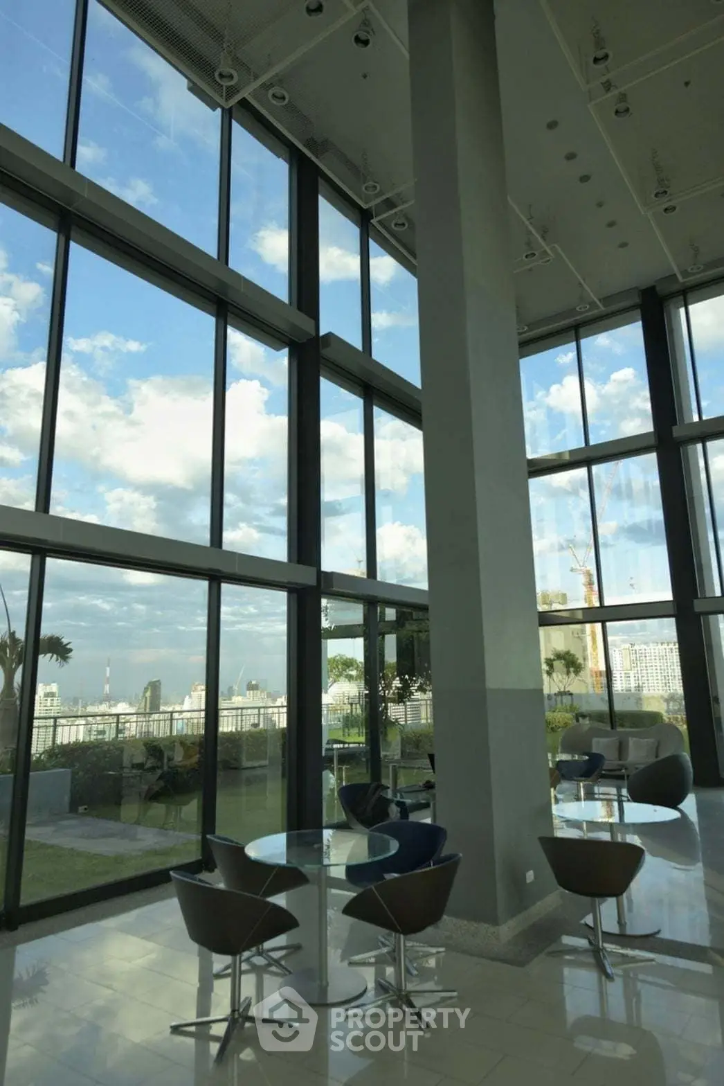 Spacious modern living area with floor-to-ceiling windows and stunning city view.