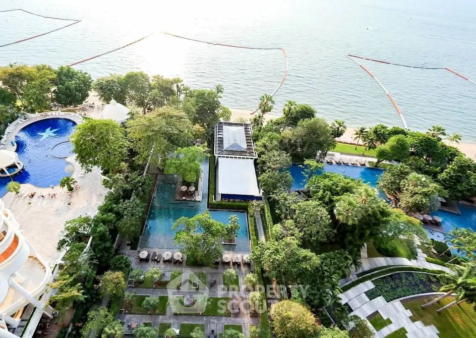 Stunning aerial view of luxury beachfront property with pools and lush gardens.