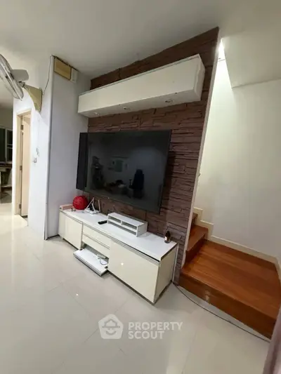 Modern living room with sleek TV setup and stylish staircase