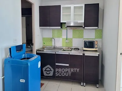 Modern kitchen with dark cabinets, microwave, and washing machine in compact layout.