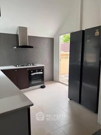 Modern kitchen with sleek appliances and open layout, featuring a gas stove and large refrigerator.