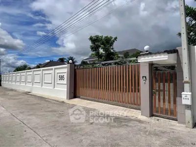 Elegant gated entrance of a modern property with high walls and secure access.