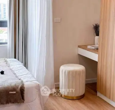 Cozy bedroom with modern decor and natural light, featuring a stylish stool and wooden accents.