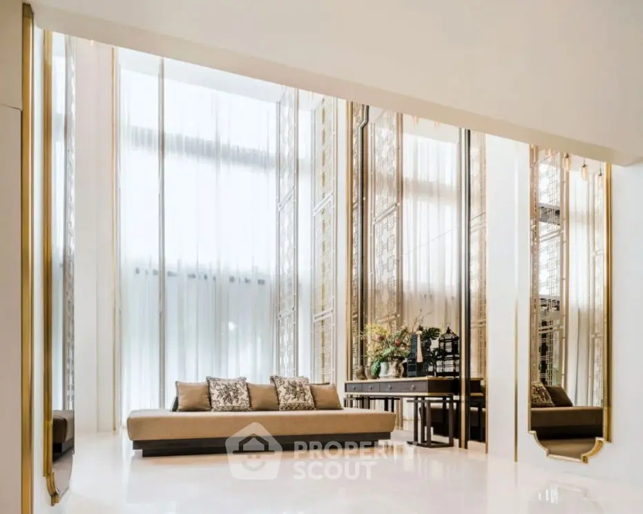 Luxurious living room with high ceilings, elegant decor, and floor-to-ceiling windows.