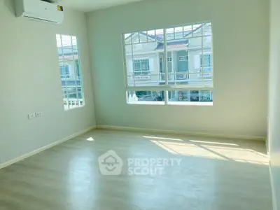 Spacious and sunlit empty room with large windows offering a view of the neighborhood, perfect canvas for personalized interior design.
