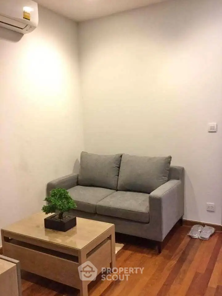 Cozy living room with modern gray sofa and wooden coffee table on polished hardwood floor.
