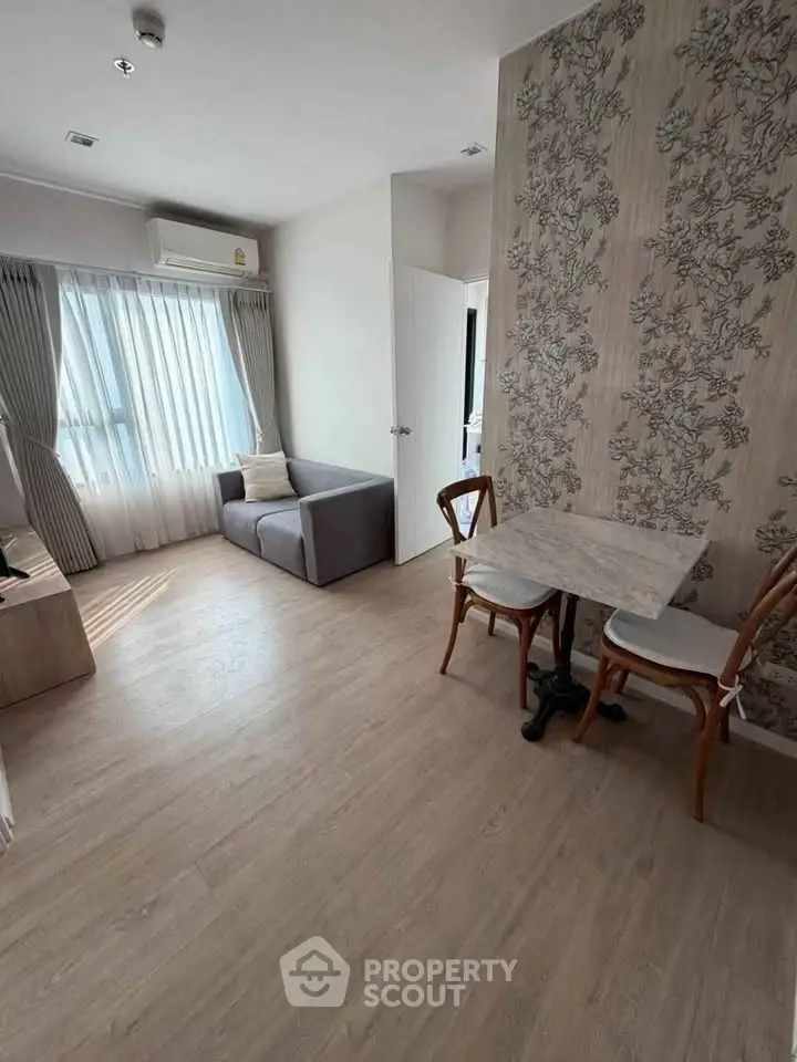 Charming living room with natural light, cozy seating, and elegant wallpaper, perfect for relaxation.