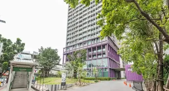 Modern high-rise building with lush greenery and urban surroundings.