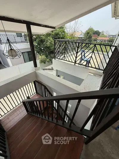 Modern multi-level balcony with stylish railing and wooden stairs, offering scenic views of surrounding greenery.