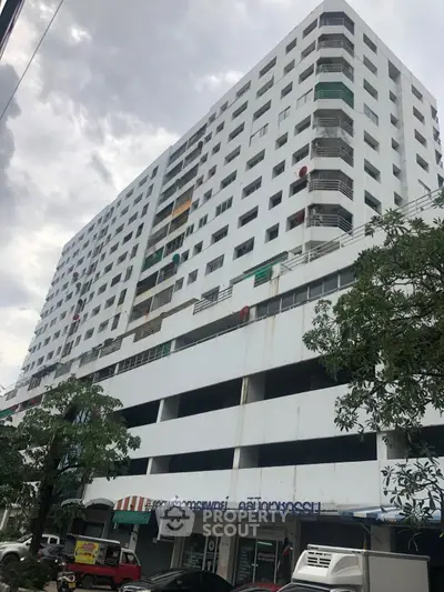 High-rise residential building with multiple balconies and street-level shops.