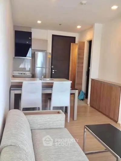 Modern apartment interior with open kitchen and cozy living area, featuring sleek furniture and contemporary design.