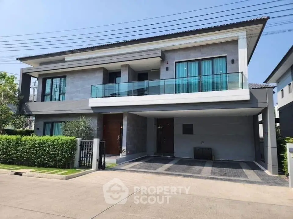 Modern two-story house with balcony and garage in a suburban neighborhood.