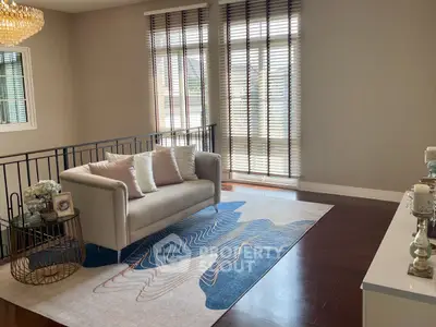 Elegant living room with modern decor and large windows, featuring a stylish sofa and chic rug.