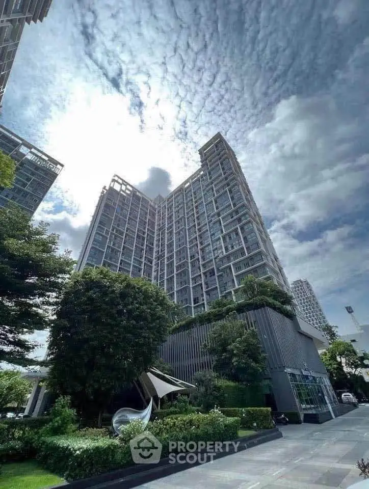 Stunning modern high-rise building with lush greenery and dramatic sky view.