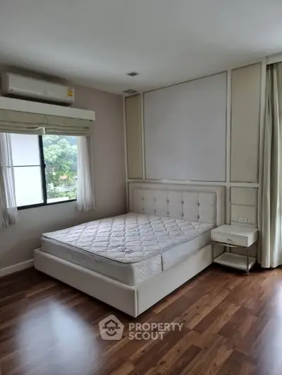 Spacious bedroom with large window and modern furnishings