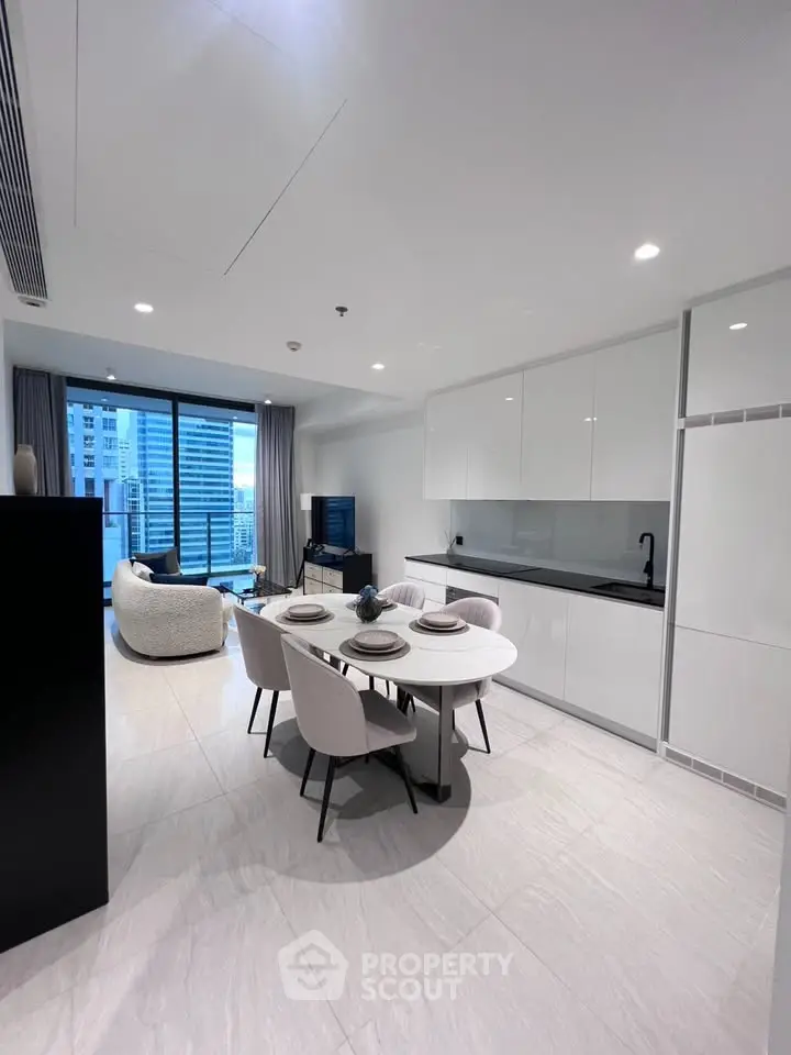 Modern open-plan kitchen and living room with city view, sleek white cabinetry, and elegant dining area.