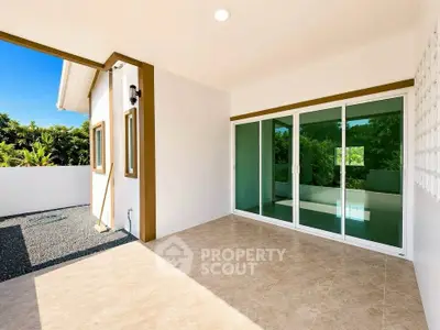 Spacious modern patio with sliding glass doors and garden view, perfect for outdoor relaxation.