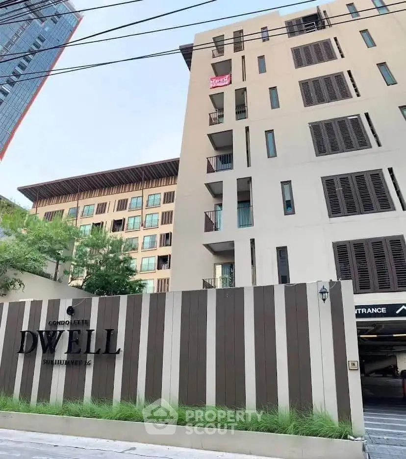 Modern condominium exterior with stylish facade and lush greenery in urban setting.