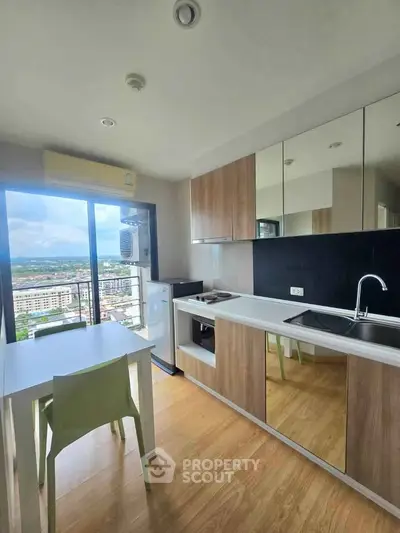 Modern kitchen with city view, sleek cabinetry, and dining area in high-rise apartment.