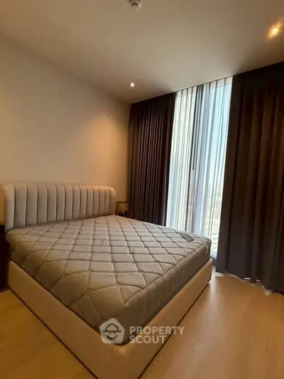 Modern bedroom with stylish bed and floor-to-ceiling windows in a high-rise apartment.