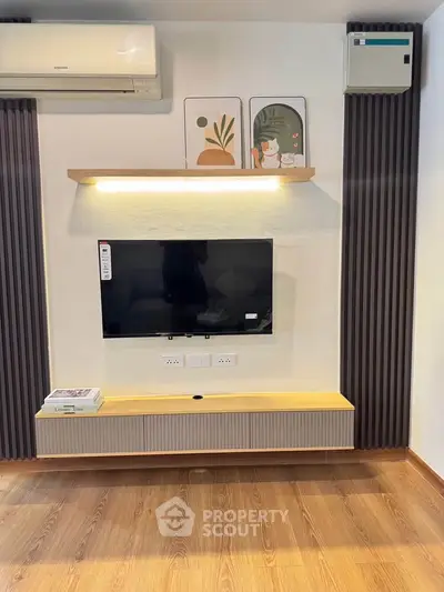 Modern living room with wall-mounted TV, stylish decor, and wooden flooring.