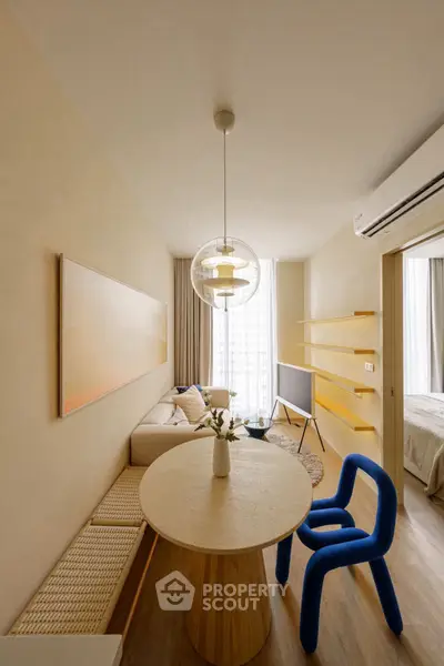 Modern living room with stylish furniture and natural light, featuring a unique blue chair and elegant decor.