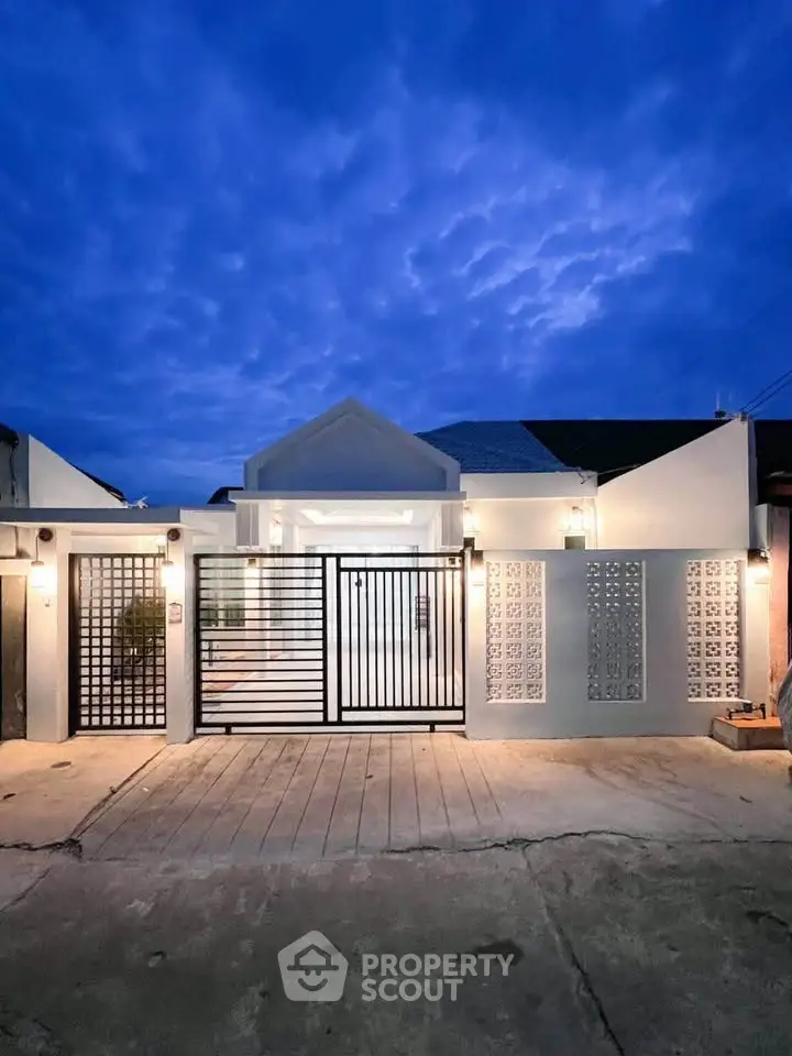 Stunning modern home exterior with elegant gate and ambient lighting at dusk.