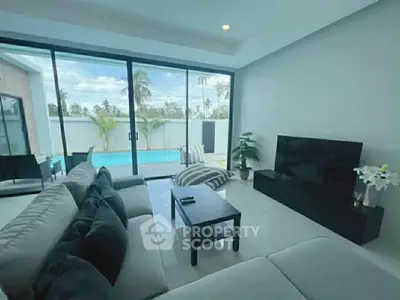 Luxurious living room with pool view and modern decor in tropical setting.