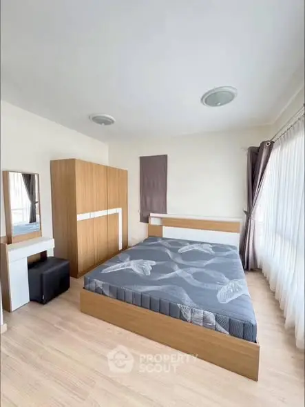 Spacious bedroom with modern furniture and large windows for natural light.