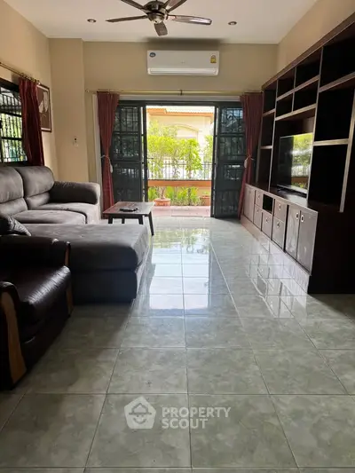 Spacious living room with modern furniture and large windows opening to a lush balcony view.