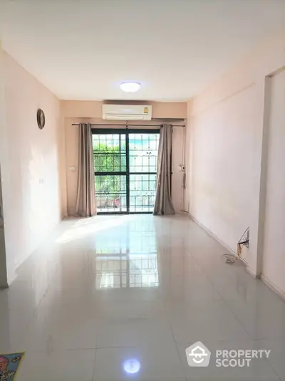 Spacious and well-lit living room with glossy tiled flooring, large windows draped with elegant curtains, and a serene view of greenery outside, perfect for a modern lifestyle.