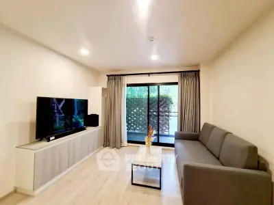 Modern living room with sleek furniture and large TV, featuring a cozy atmosphere and natural light.