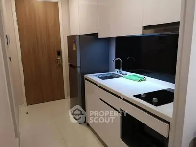 Modern compact kitchen with sleek white cabinetry and stainless steel appliances in a stylish apartment.