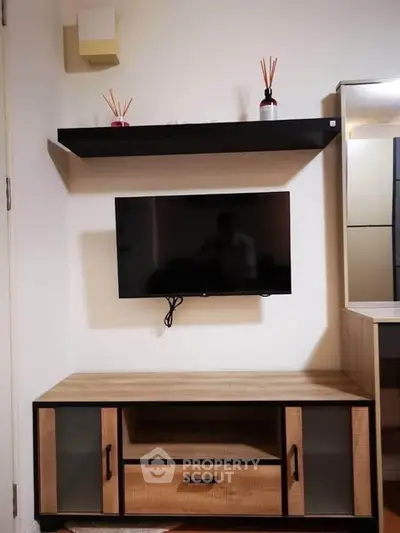 Modern living room with wall-mounted TV and stylish wooden cabinet.