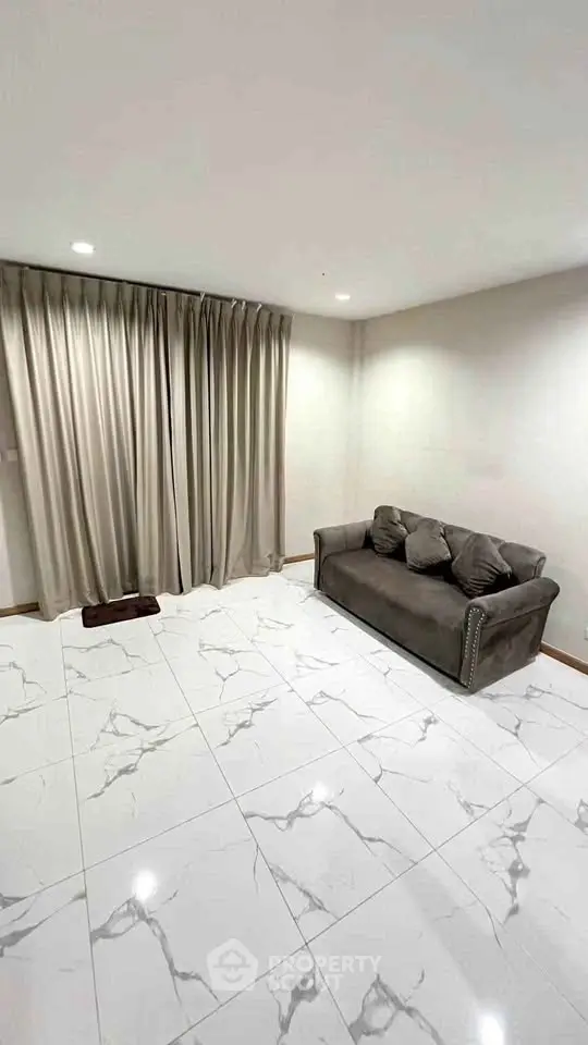 Spacious living room with elegant marble flooring and cozy sofa, perfect for relaxation.