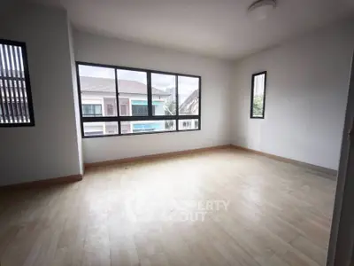 Spacious empty room with large windows and wooden flooring, perfect for customization.